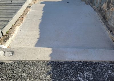 A concrete ramp connects a paved surface to an upper sidewalk, bordered by a stone wall and wooden platform—showcasing quality paving services available in Edgewood MD.